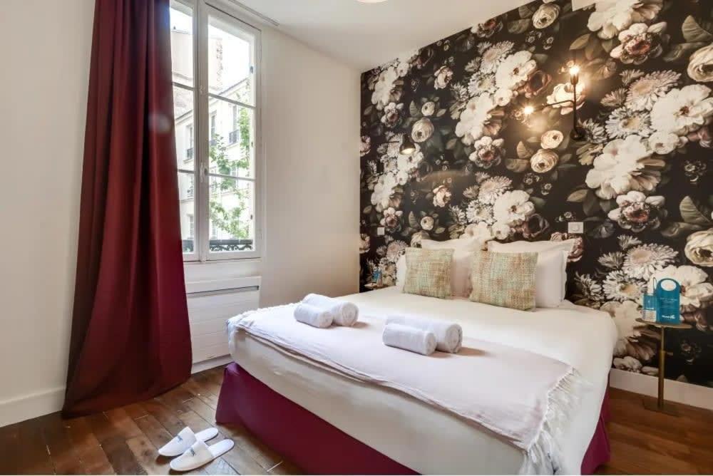 - une chambre avec un grand lit et du papier peint floral dans l'établissement Renovated 2BD next to Jardins du Luxembourg, à Paris