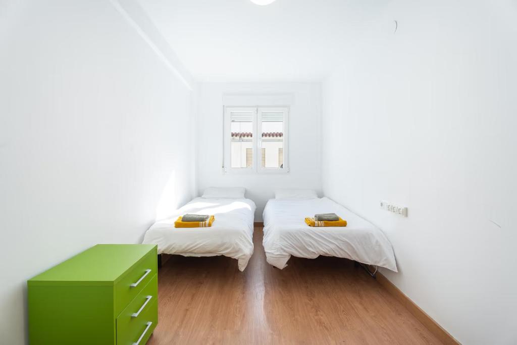 Cette chambre blanche comprend 2 lits et une armoire verte. dans l'établissement Bungalow PLAYA POBLA DE FARNALS, à Las Canteras
