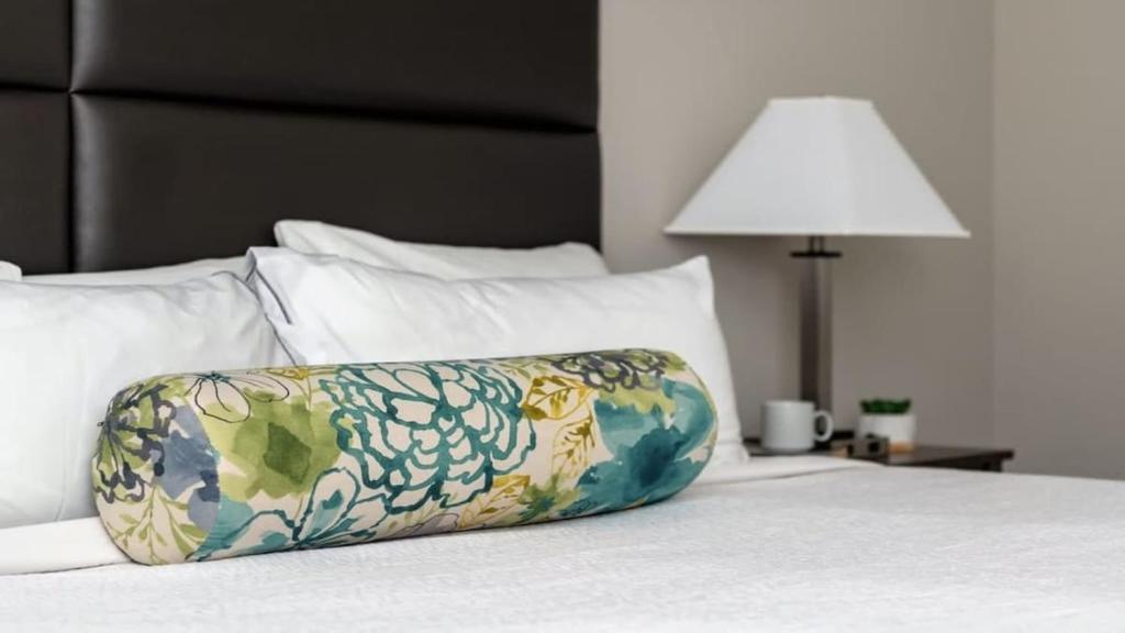 un cuscino posto sopra un letto con lampada di Bold CozySuites with gym, roof #6 a Dallas