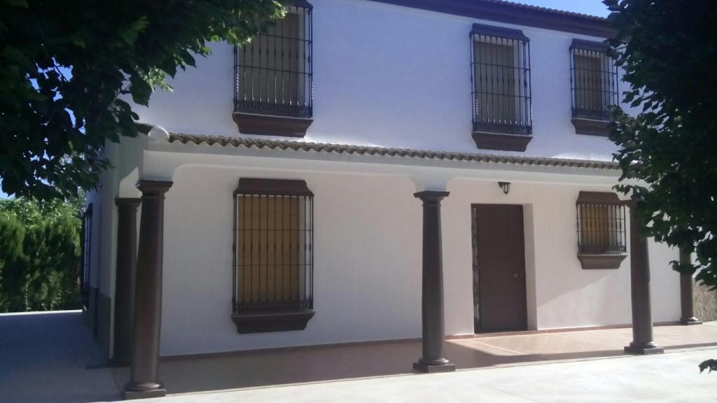 ein weißes Haus mit Säulen und vergitterten Fenstern in der Unterkunft Casa Tita Carmen in Córdoba
