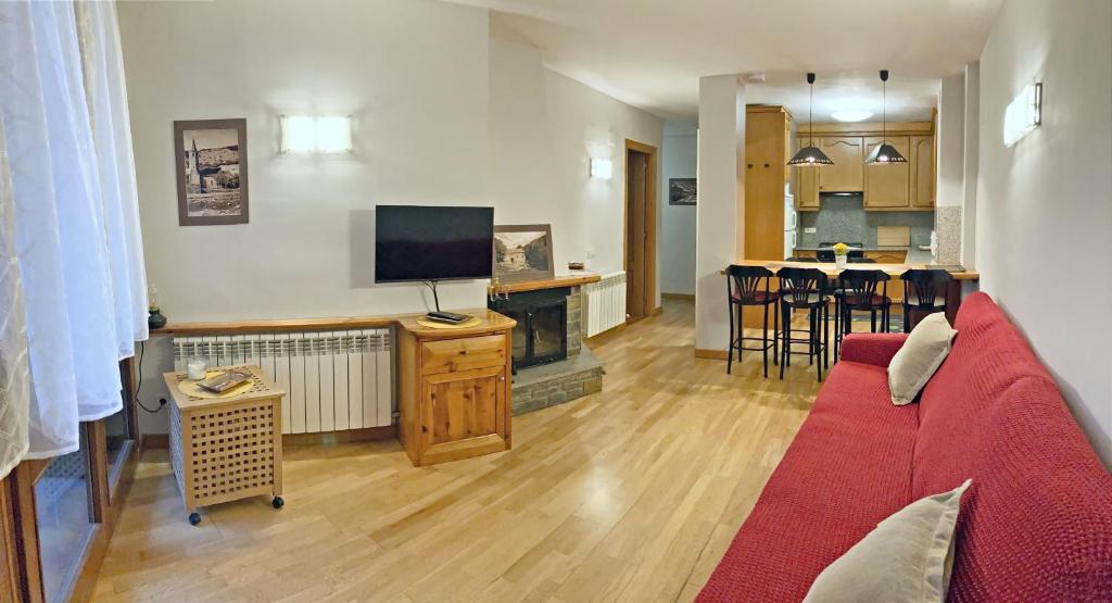 sala de estar con sofá rojo y chimenea en Apartamento Casovall, en Esterri d'Àneu
