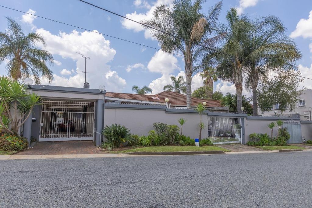 a house with a gate and palm trees at Roslin Apartments in Johannesburg