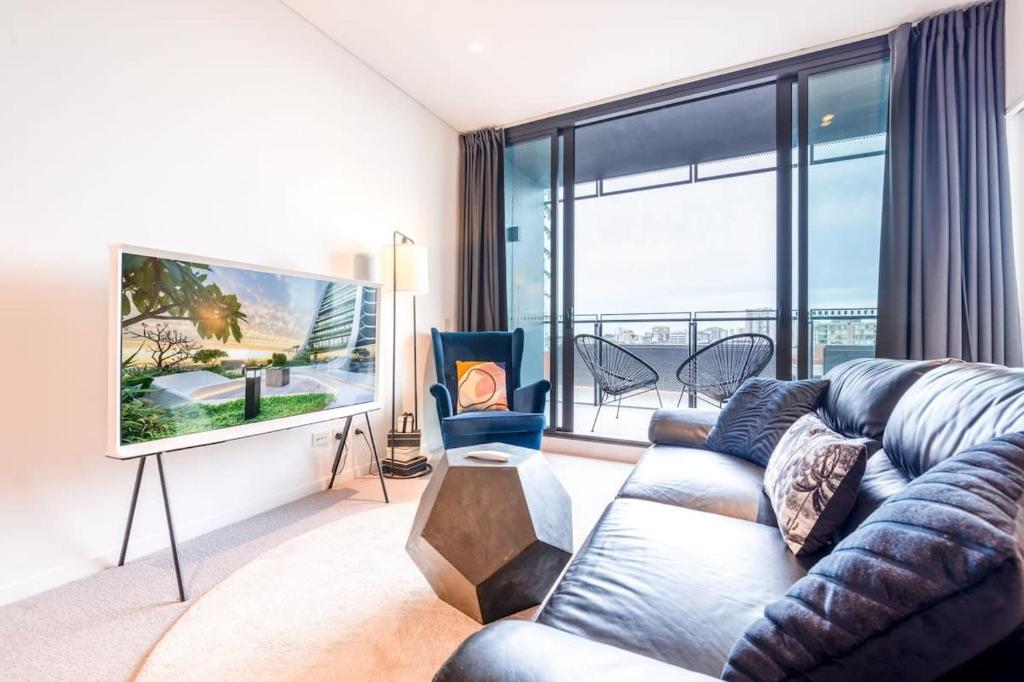 uma sala de estar com um sofá e uma grande janela em Contemporary 2-Bed Apartment Minutes to City em Sydney