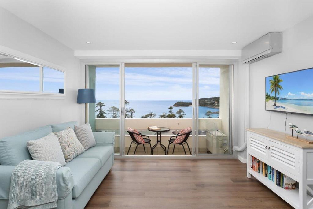 a living room with a couch and a view of the ocean at Modern Manly Apartment with Stunning Views, Pool in Sydney