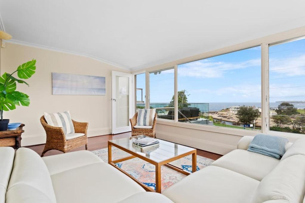 a living room with white furniture and a large window at Clovelly Beach House - Sea, Sand and Exclusivity in Sydney