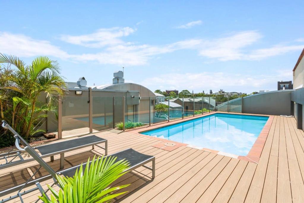 a swimming pool on top of a house with a wooden deck at Charming 1-Bed Apartment Close to Shops and Parks in Sydney