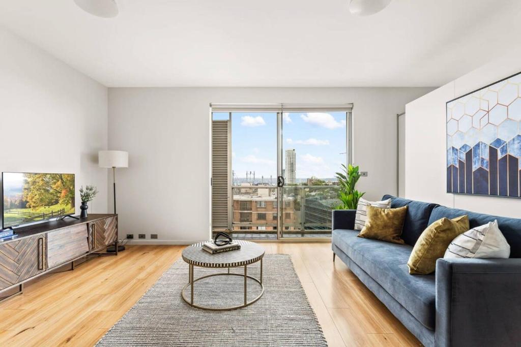 a living room with a blue couch and a tv at Executive 1-Bed Apartment with City Views in Sydney