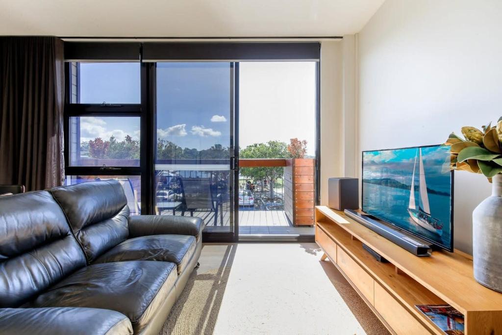 a living room with a couch and a flat screen tv at Gorgeous 2-Bed Apartment By Shops and the River in Batemans Bay