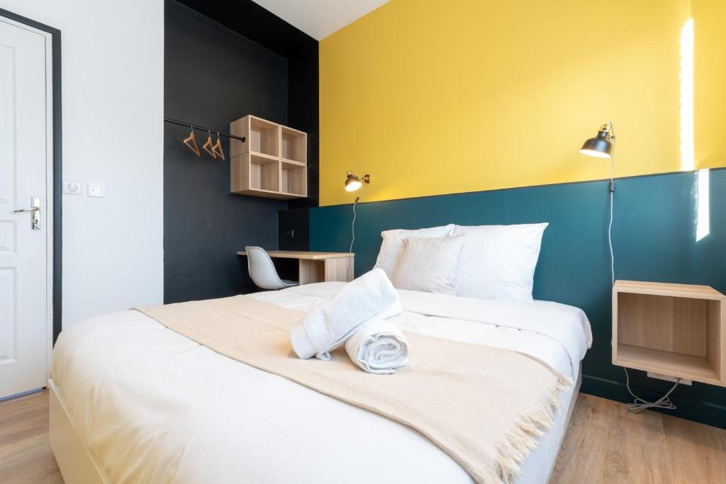 a bedroom with a large bed with a yellow and blue wall at Marcq-en-Baroeul - App art deco equipped for 2! in Marcq-en-Baroeul