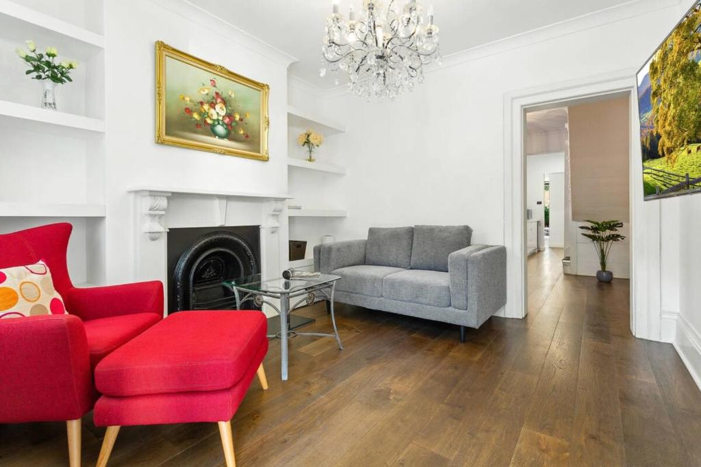 - un salon avec une chaise rouge et un canapé dans l'établissement Traditional 2-Bed Terrace House in Millers Point, à Sydney