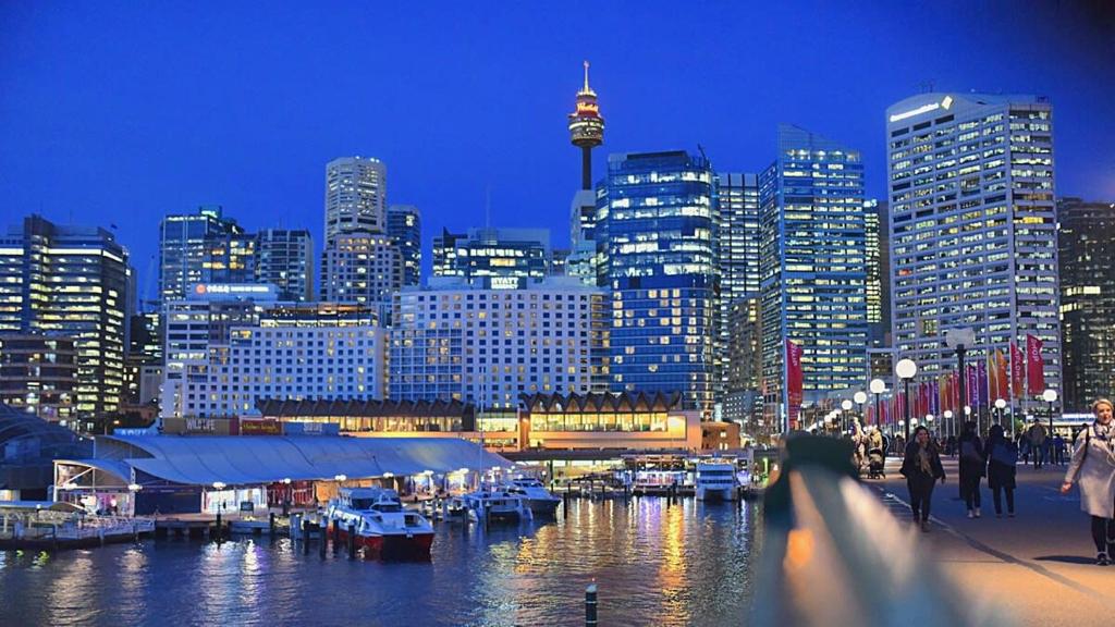 a view of a city at night with boats in the water at Superb 3-Bed Victorian Terrace by Darling Harbour in Sydney