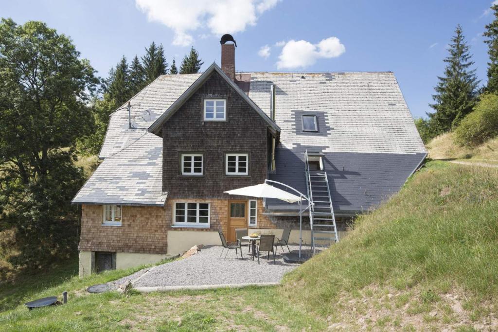 una casa en una colina con una mesa y una sombrilla en Fewo Titisee im Kaspershäusle 