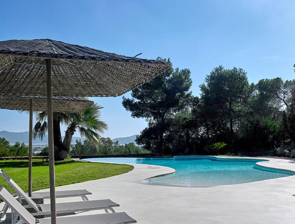 una piscina con sillas y sombrilla en Villa Alexia - San Jose en Sant Francesc de s'Estany