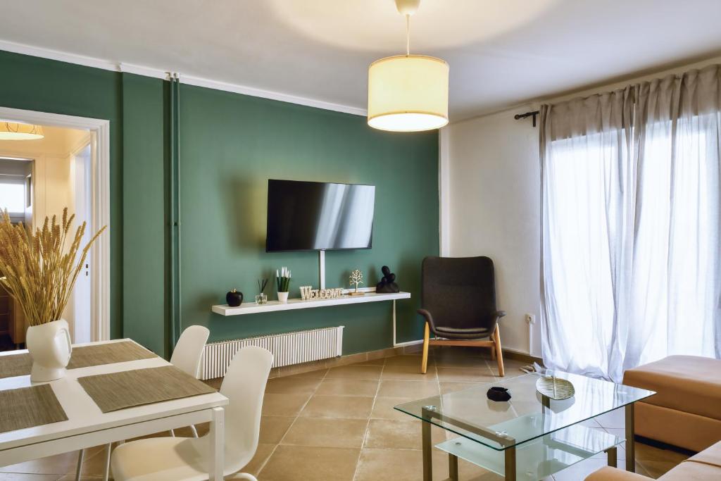 a living room with green walls and a table and chairs at medusa apartment in glyfada in Athens