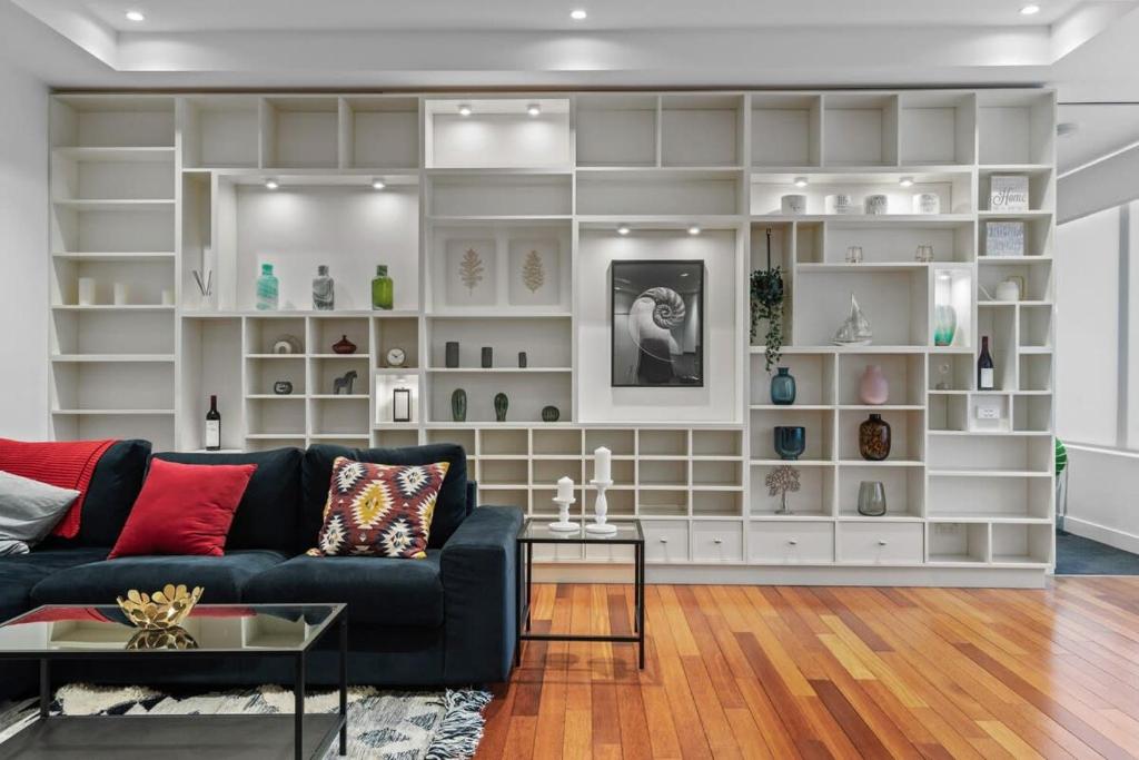 a living room with a black couch and white shelves at Stylish and Spacious 2-Bed Apartment Melbourne in Melbourne