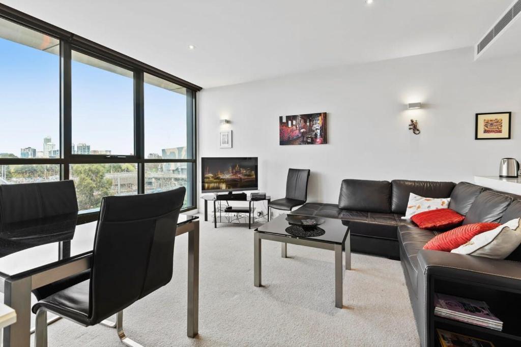 a living room with a couch and chairs and windows at Beautiful 1-Bed Unit in The Heart of Melbourne in Melbourne