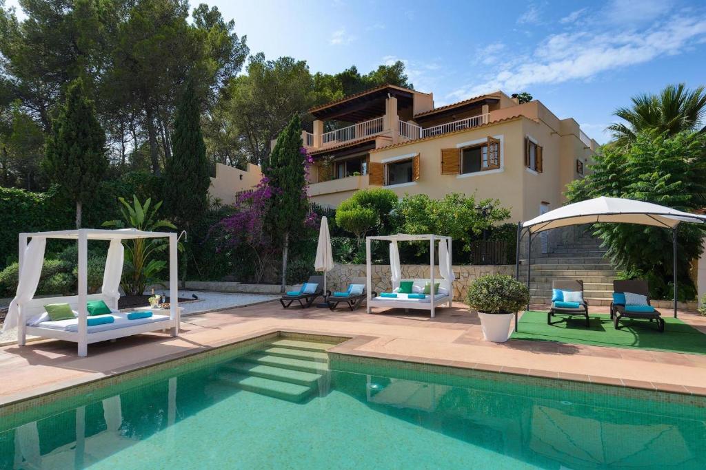 une piscine avec des chaises et une maison en arrière-plan dans l'établissement Villa Claudia - Ibiza, à Sant Rafael de Sa Creu