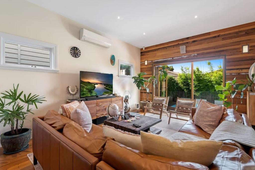 a living room with a couch and a tv at Sophisticated 2-Bed House with a Pool in Seddon