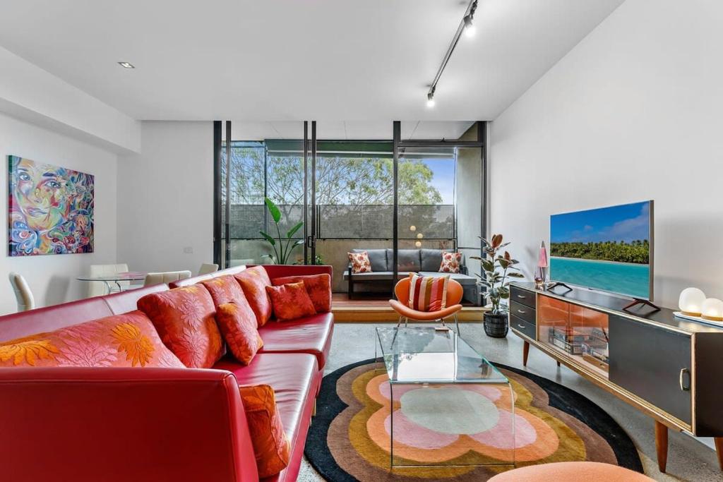 a living room with a red couch and a glass table at Vibrant 2-Bed Apartment Near St Kilda Beach in Melbourne