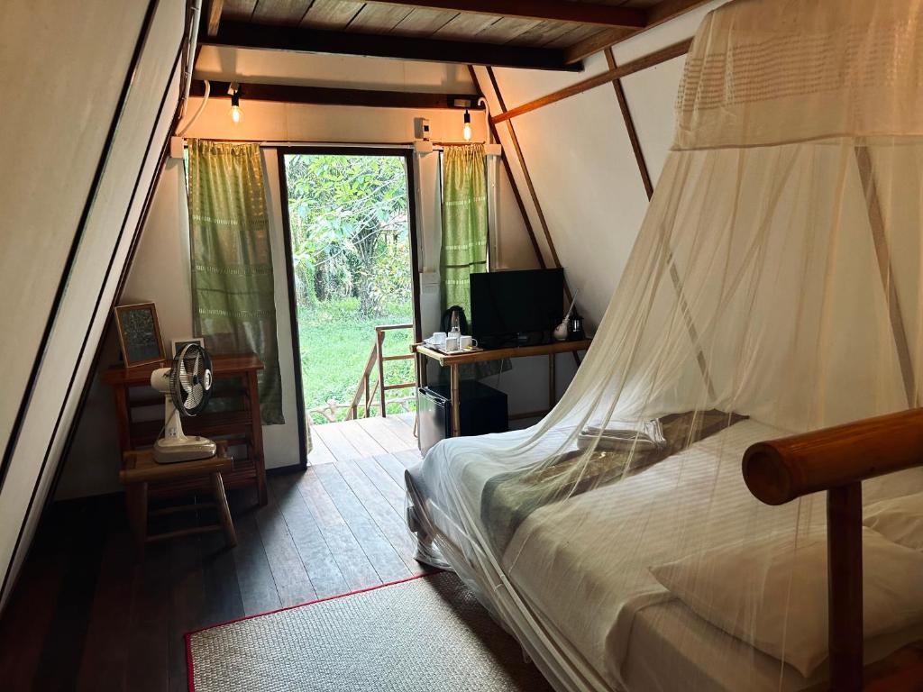 a bedroom with a bed and a desk and a window at Khao Sok Paradise Resort in Khao Sok