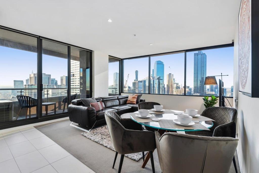 a living room with a couch and a table with chairs at Chic Central Pad with City Views, Pool and Gym in Melbourne