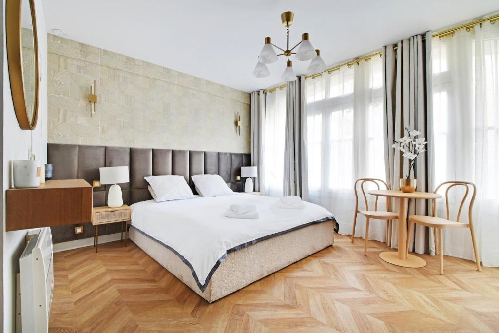 une chambre avec un grand lit blanc et du parquet dans l'établissement le bon plan, à Paris