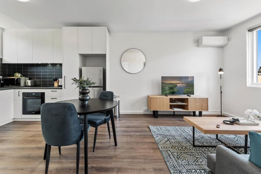 eine Küche und ein Wohnzimmer mit einem Tisch und Stühlen in der Unterkunft Polished 1-Bed St Kilda Pad in Prime Location in Melbourne