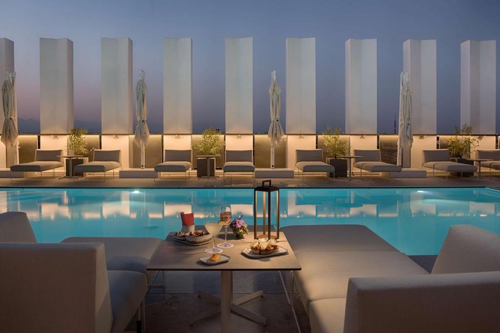 a pool with chairs and a table next to a hotel at NH Collection Milano CityLife in Milan