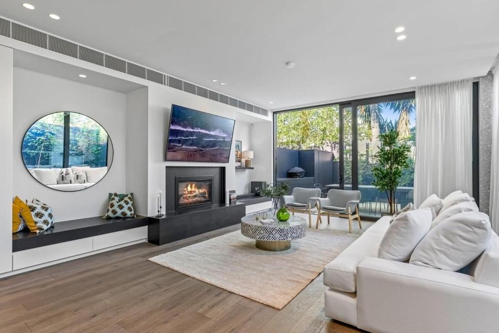 een woonkamer met een witte bank en een open haard bij Impeccably Chic 3-Bed House by Fawkner Park in Melbourne