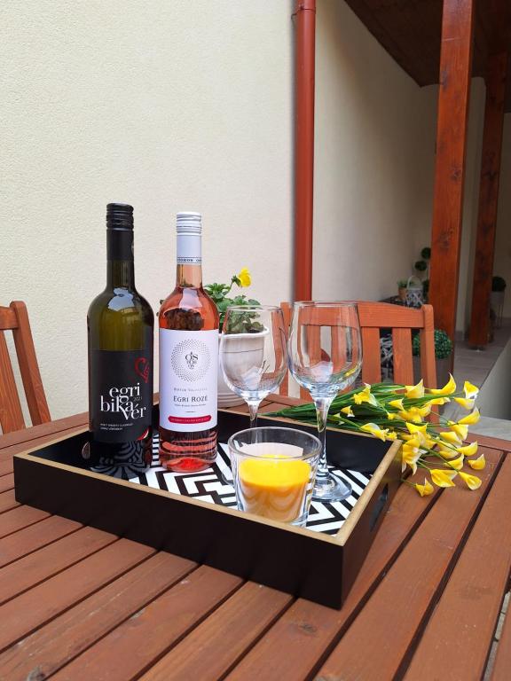 two bottles of wine and glasses on a tray on a table at Várfal apartman II in Eger