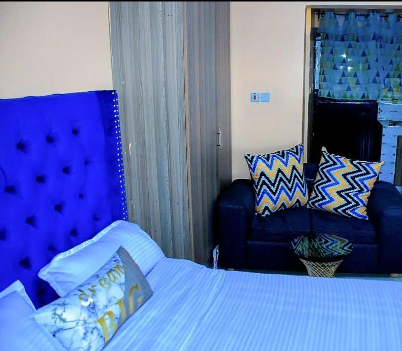 a bedroom with a blue bed and a couch at Studios in roysambu in Nairobi