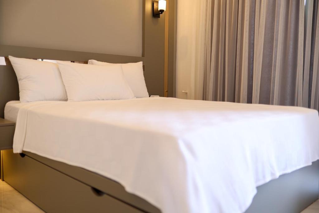 a bed with white sheets and pillows in a room at Akdeniz Yaşam Otel in Silifke