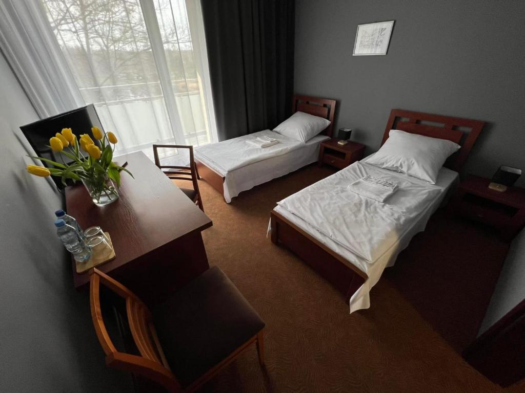 una habitación con 2 camas y una mesa con flores en OLIMPIA Ośrodek Przygotowań Sportowych, en Rybnik