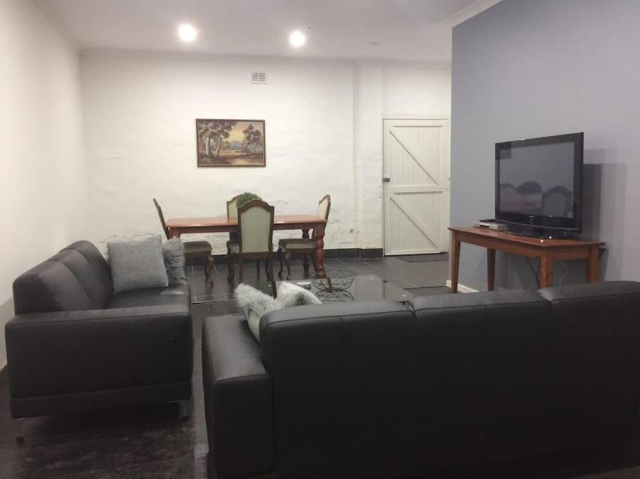 ein Wohnzimmer mit einem Sofa und einem Tisch mit einem TV in der Unterkunft Urban Warehouse in Queanbeyan