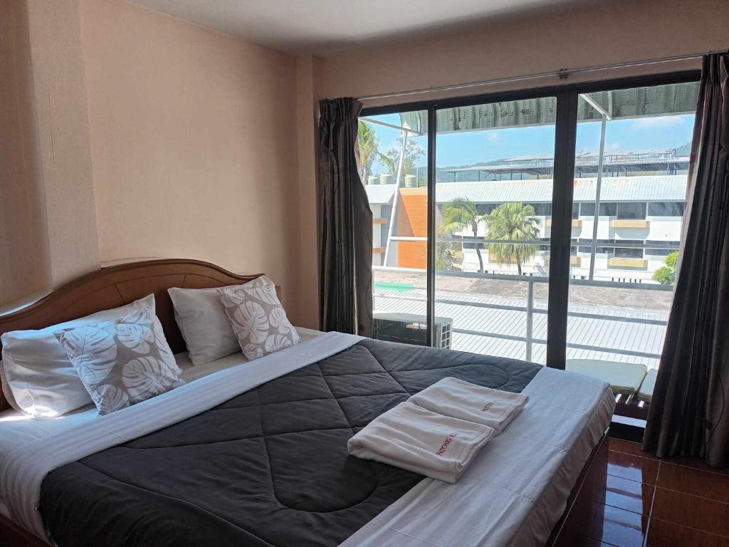 1 dormitorio con 1 cama grande y toallas. en Patong Rose Guest House, en Patong Beach