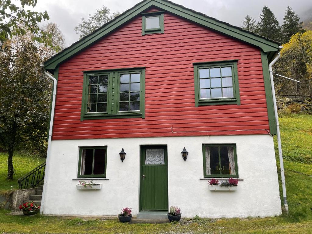 a red and white house with a green door at Kvammen in Sæbø