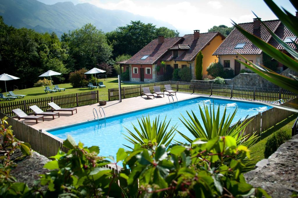 a swimming pool with chairs and a house at Hotel Rural La Lluriga in La Galguera