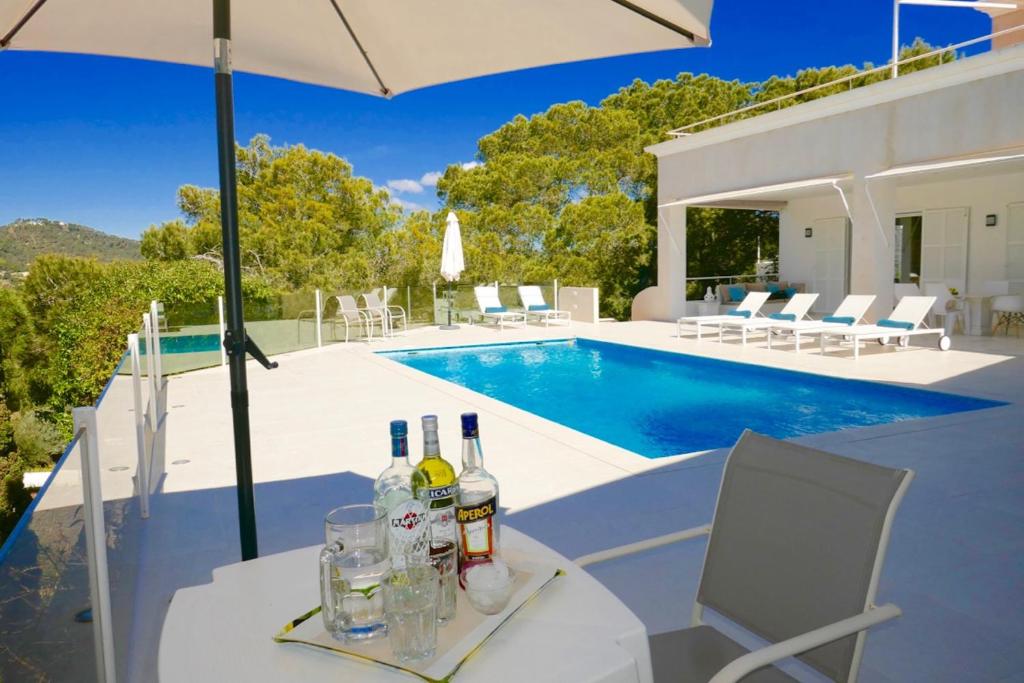 Villa Dream - Santa Eulalia في كالا يونغا: طاولة عليها زجاجات من النبيذ بجوار حمام سباحة
