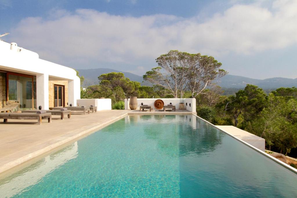 una piscina infinita en una villa con montañas en el fondo en Villa Marte - San Jose, en Sant Josep de sa Talaia