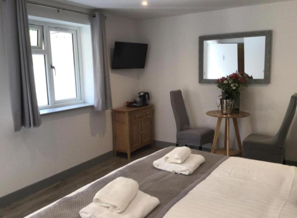 a bedroom with a bed and two chairs and a television at Hunters Lodge in Barnstaple