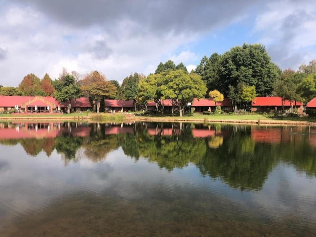 vistas a un lago con árboles y edificios en Critchley Hackle Lodge, en Dullstroom