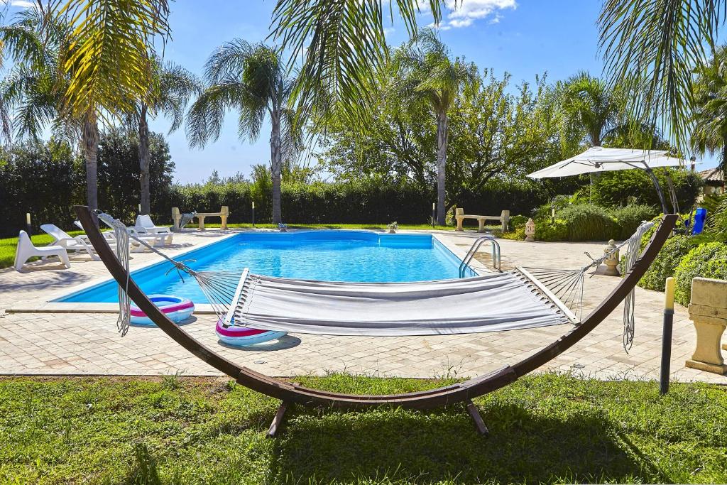 a hammock sitting in front of a swimming pool at Villa Claudia in Castelvetrano Selinunte