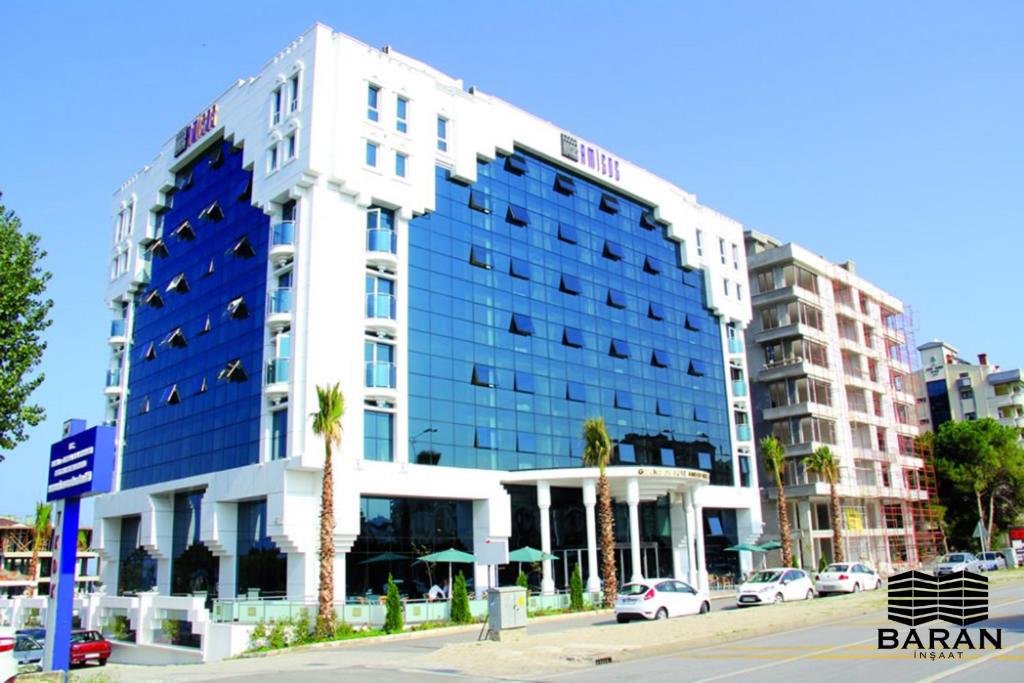 a large white building with palm trees in front of it at Grand Amisos Hotel in Samsun