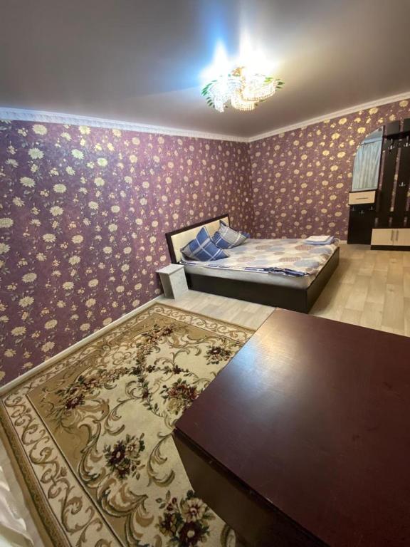 1 dormitorio con cama, mesa y alfombra en 1-x Квартира в центре города по доступной цене, en Rudny