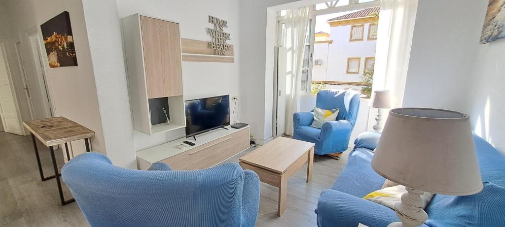 a living room with blue chairs and a television at Paula Beach Malaga in Málaga