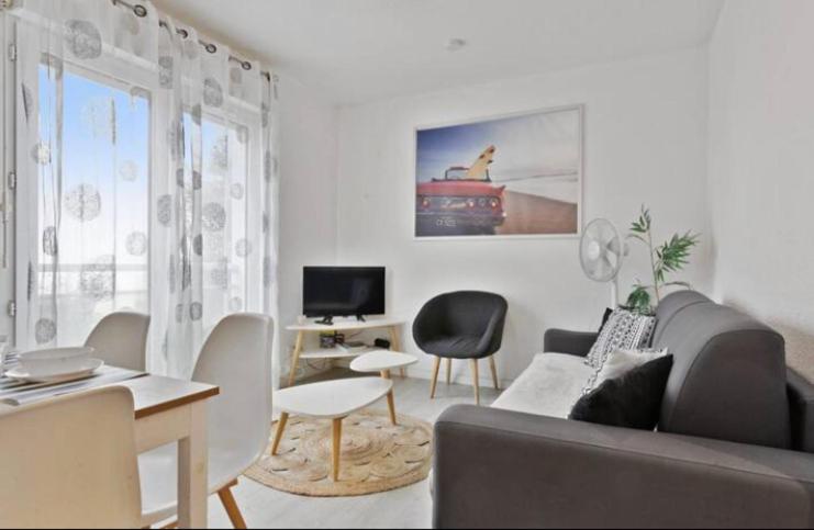 een woonkamer met een bank en stoelen en een tv bij Appartement lumineux à Biarritz in Biarritz