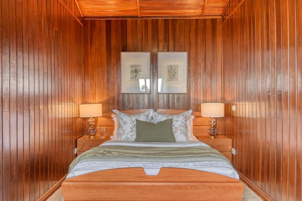 1 dormitorio con paredes de madera y 1 cama con 2 lámparas en Chalet do Relogio d'Agua, a Home in Madeira, en Ponta do Sol