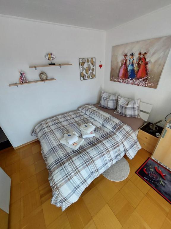 1 dormitorio con 1 cama con manta a cuadros en Joli studio avec terrasse et vue EXCLUSIVEMENT POUR NON FUMEURS en Belmont-sur-Lausanne