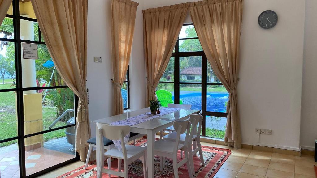- une salle à manger avec une table, des chaises et de grandes fenêtres dans l'établissement MA Villa 993, A Famosa Resort, à Kampong Alor Gajah