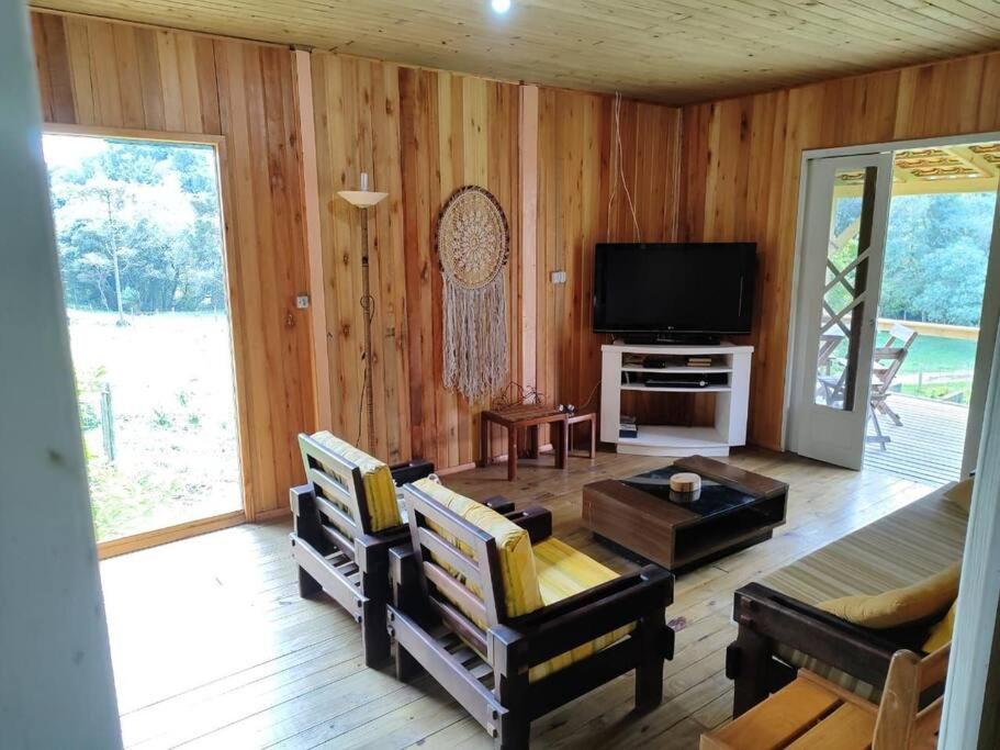 a living room with wood paneling and a television at Casa Serrana in Barracão